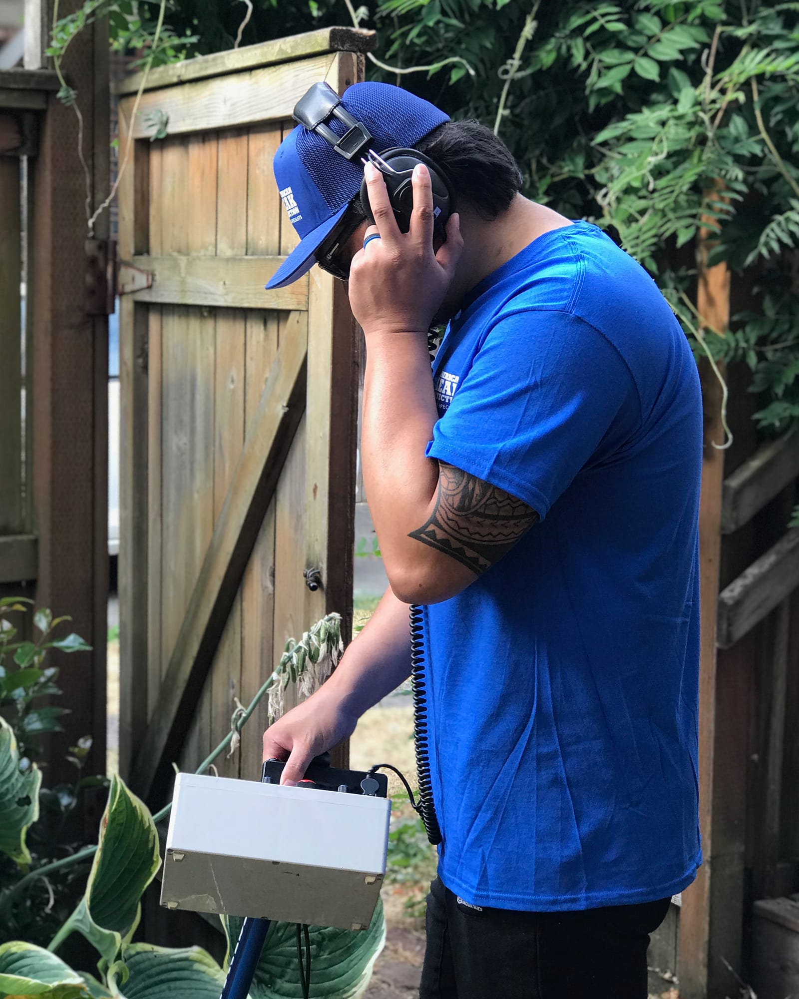 American Leak Detection technician using acoustic listening equipment during an exterior leak diagnostic.