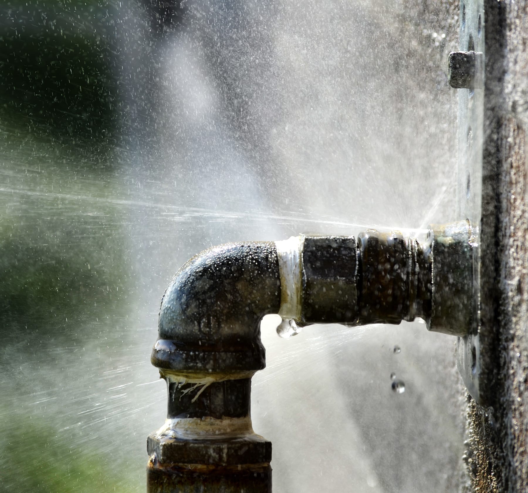 Pressurized pipe joint spraying water from an active leak.